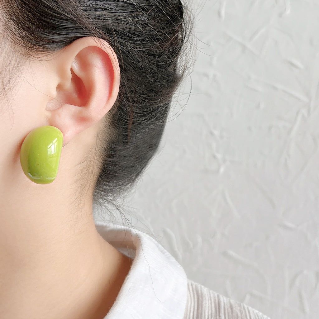 JR Fashion Accessoriesの夏コレクションのポップスタイルを披露する、鮮やかな緑のレジンビッグスタッドイヤリングを着用した女性のクローズアップ。