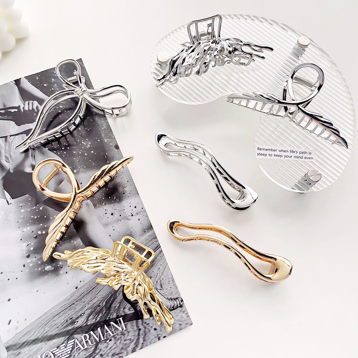 Una colección de elegantes clips de garra de aleación metálica para mujeres, con varios diseños en acabados dorados y plateados, exhibidos ordenadamente para una presentación de producto.
