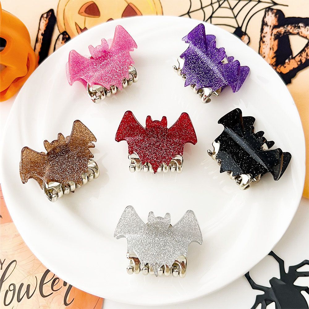 A collection of six colorful glittery bat-shaped hair claw clips for Halloween, displayed on a white surface.