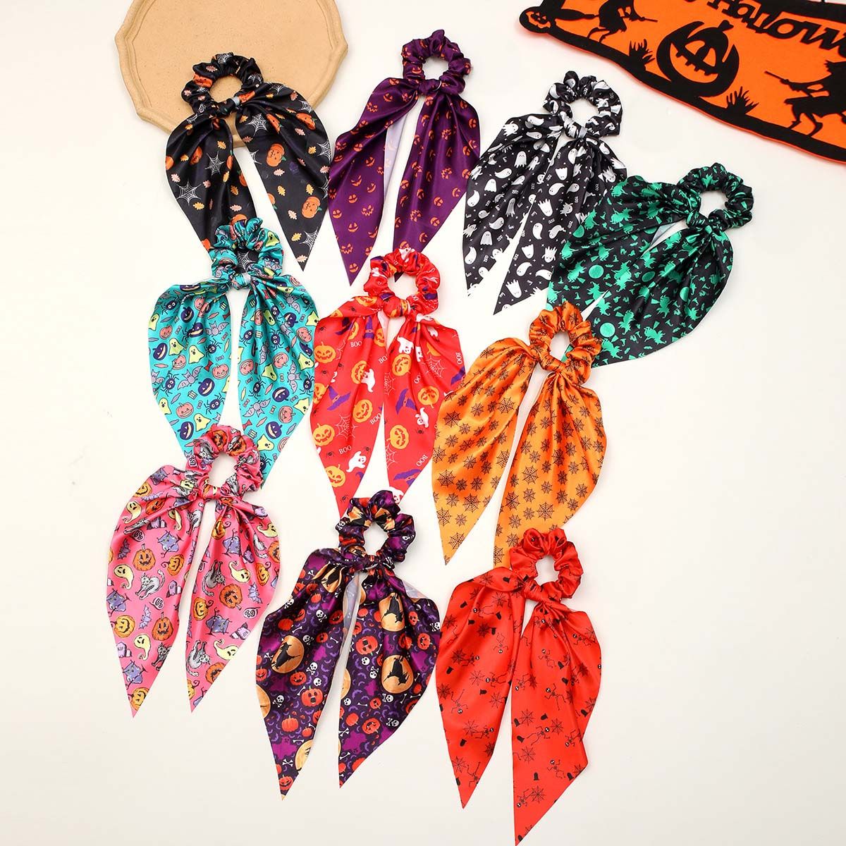 Een collectie kleurrijke Halloween-thema lint scrunchies met lange staarten, met verschillende spooky en leuke patronen zoals pompoenen, spoken en heksen.