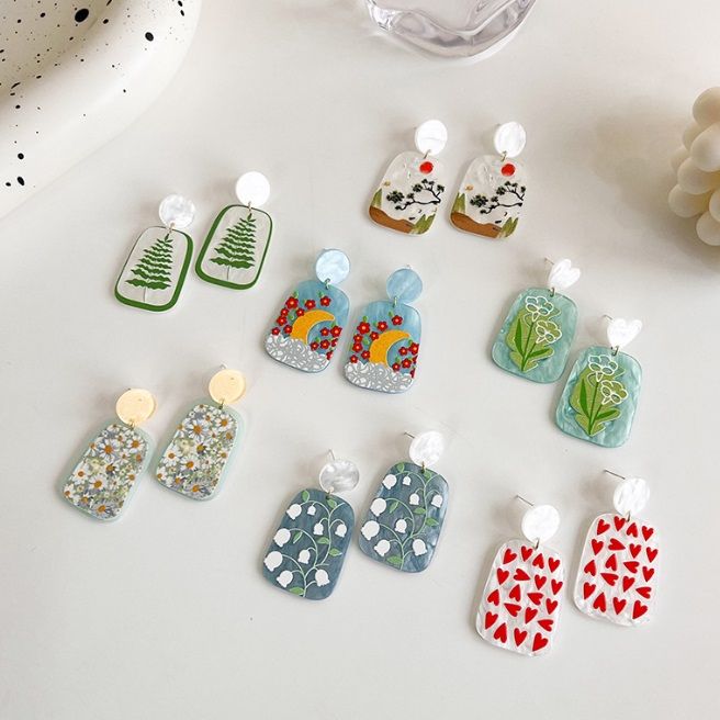 JR Fashion Accessoriesのカラフルな幾何学模様と抽象模様のレジンとアクリルイヤリングのコレクション、白い背景に展示されています。