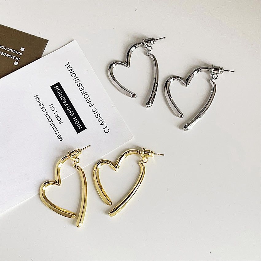 Un conjunto de pendientes de corazón chapados en oro de 14K y acabados en plata, que muestran el diseño minimalista y la construcción de latón de alta calidad para colecciones de joyería al por mayor.