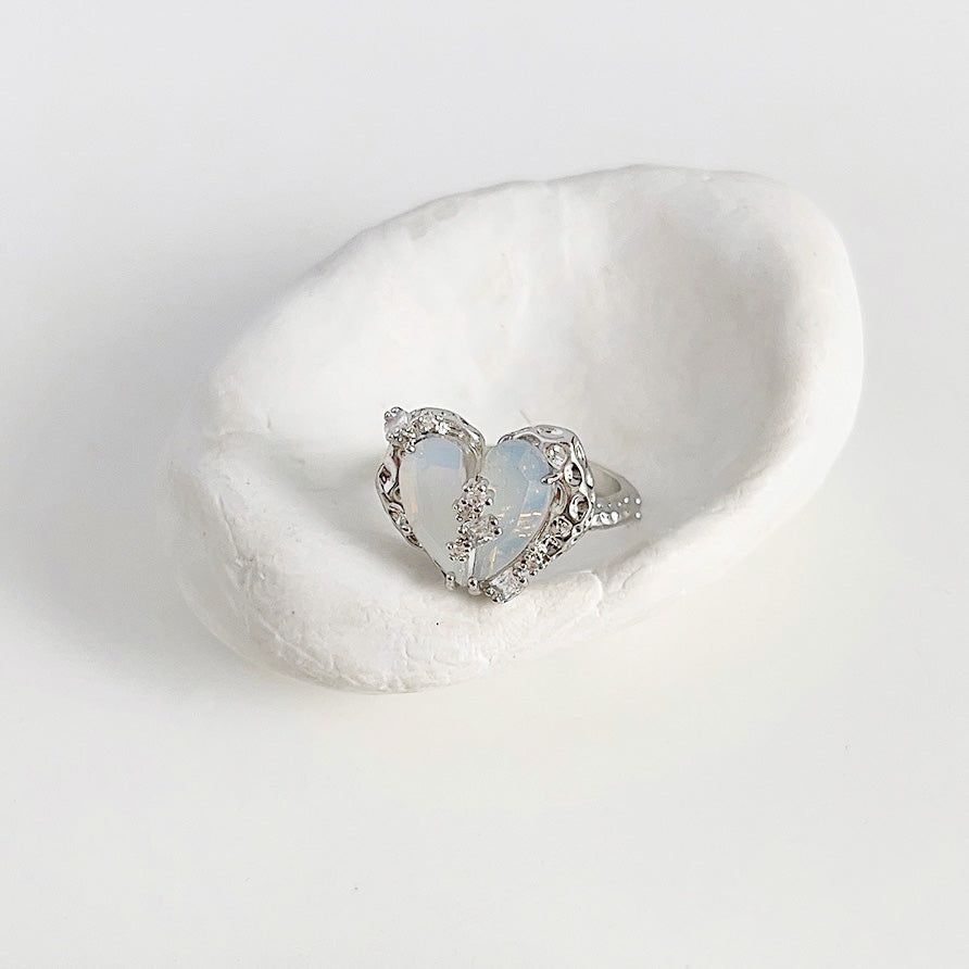 Un impresionante anillo chapado en plata del conjunto ajustable, con una piedra de ópalo en forma de corazón rodeada de acentos de cristal brillante.