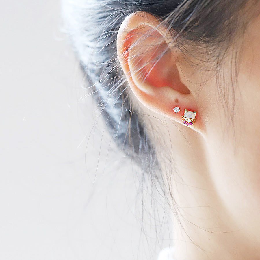 Una vista ravvicinata di una donna che indossa un carino orecchino a bottone a forma di gatto in argento sterling 925 con una pietra di opale scintillante.