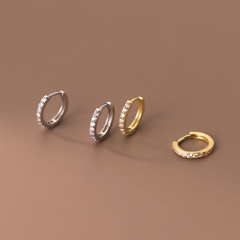 Una vetrina promozionale di orecchini a cerchio huggie geometrici semplici in zirconia in argento sterling 925, mostrando opzioni di colore sia argento che oro.