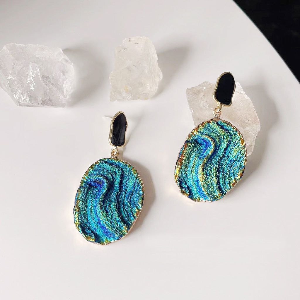 A pair of 14k gold-plated drop earrings featuring a unique and colorful Klein blue starry-sky texture, set against a clean white background.