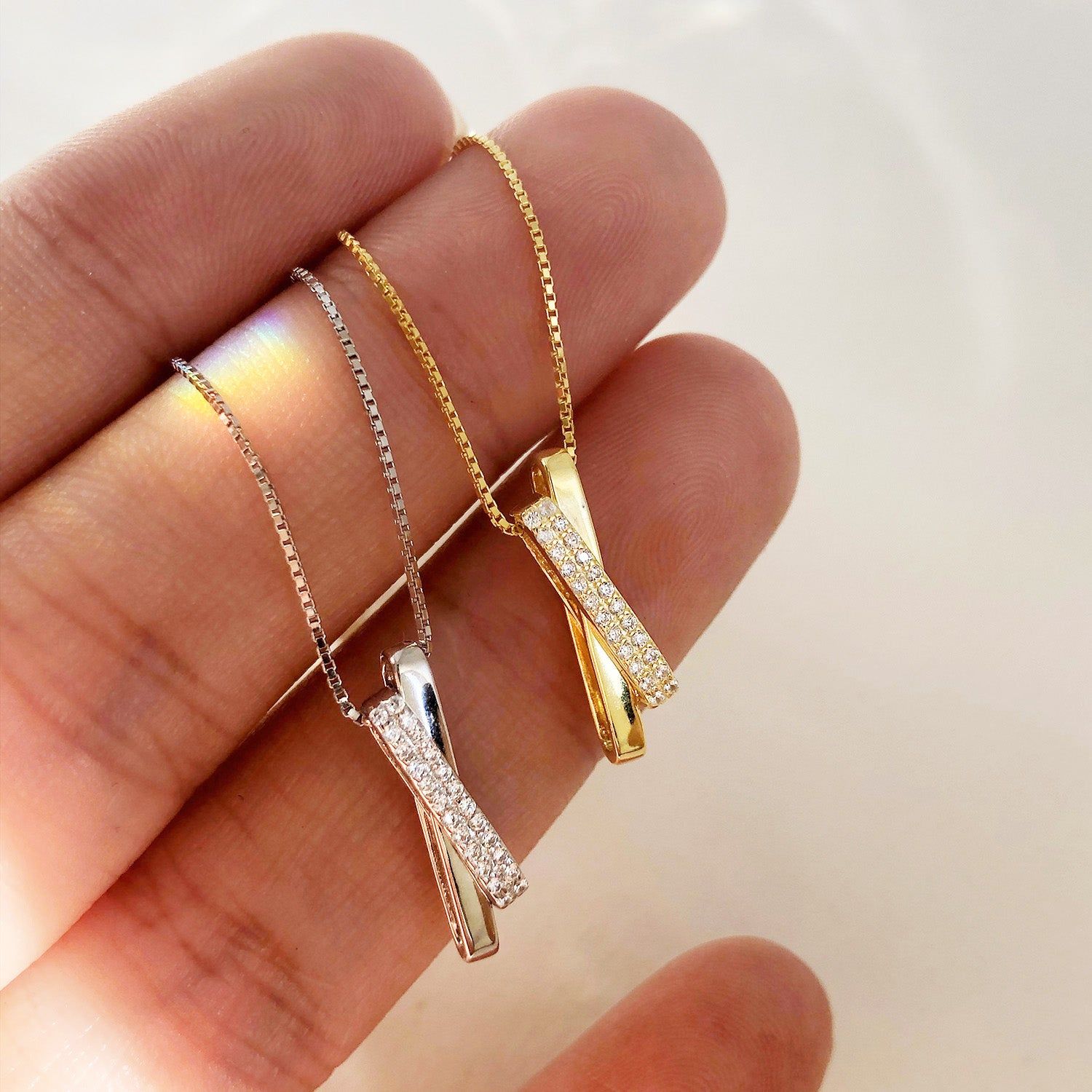 A set of 925 sterling silver necklaces with pave CZ cross and rectangle interlocking pendants, shown in both silver and gold finishes.