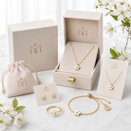 Aangepaste sieradenverpakking display met witte emaille bloemenhalskettingen, oorbellen, ring en een gouden sliderarmband.