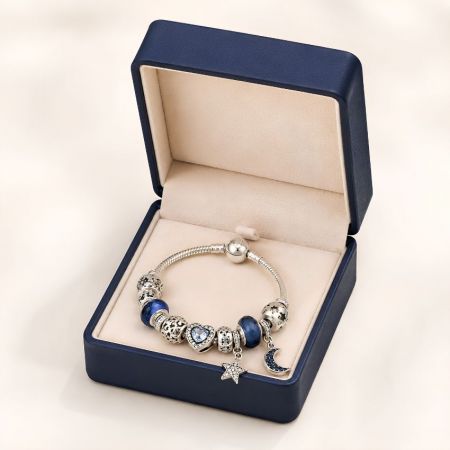 Marineblauwe leren armbanddoos open met een zilveren armband met hemelsblauwe kralen en een sterpendant.