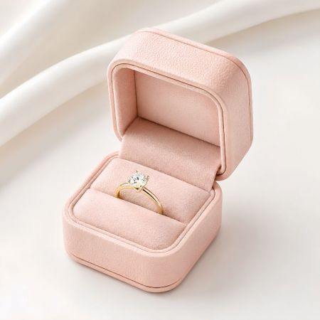 Roze leren verlovingsringdoos open met een klassieke solitaire diamanten ring met een gouden band.