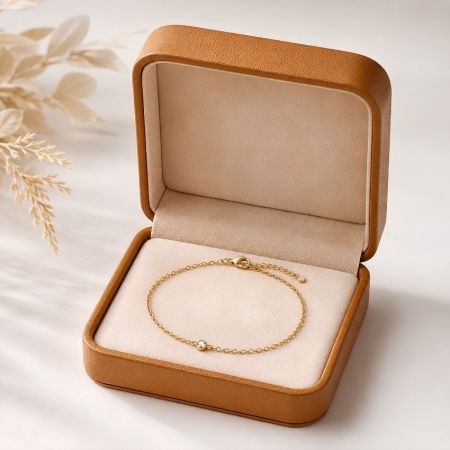 Bruine leren kettingarmband geschenkdoos met een minimalistische gouden kettingarmband met een enkele kristal.