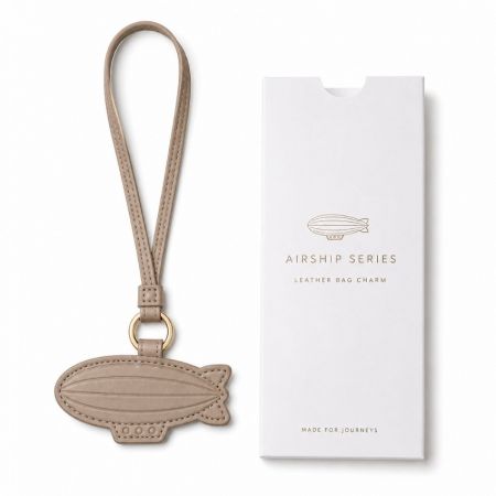 Taupe airship series leather bag charm with premium branded retail gift packaging for travel brands.