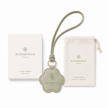 Custom embossed logo floral leather bag charm with matching branded box and drawstring pouch set.