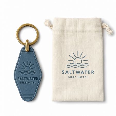 Llave de hotel de cuero azul con logo de resort de surf en relieve junto a una bolsa de algodón con cordón de marca.