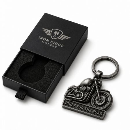 Llavero de metal de motocicleta 3D de fundición antigua para mercancía al lado de una caja de regalo premium con cajón deslizante negro.