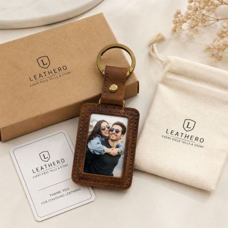 Promotional custom leather photo frame keychain with engraved brand logo and canvas drawstring pouch packaging.