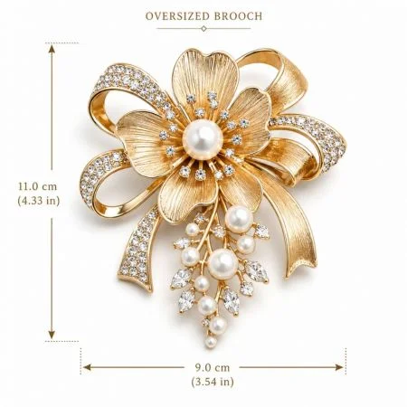 Oversized Brooch - Oversized gold floral ribbon brooch measuring 11.0 cm by 9.0 cm featuring crystals and pearl drops.