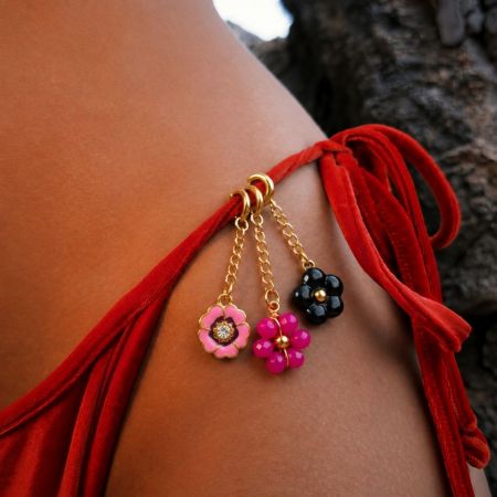 Close-up of tarnish-free gold flower charms clipped onto a velvet bikini tie, showcasing durable swimwear hardware.