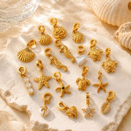 Charms de oro inspirados en el océano al por mayor dispuestos sobre piedra, mostrando fabricación de alta calidad para compradores internacionales de joyería.