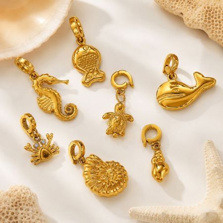 Encantos de criaturas marinas de oro variados, incluyendo caballito de mar, tortuga y ballena, exhibidos planos para la compra al por mayor de joyería.
