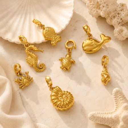 Encantos de vida marina de oro premium dispuestos sobre un fondo de piedra texturizada junto a conchas marinas, perfectos para líneas de joyería de verano.