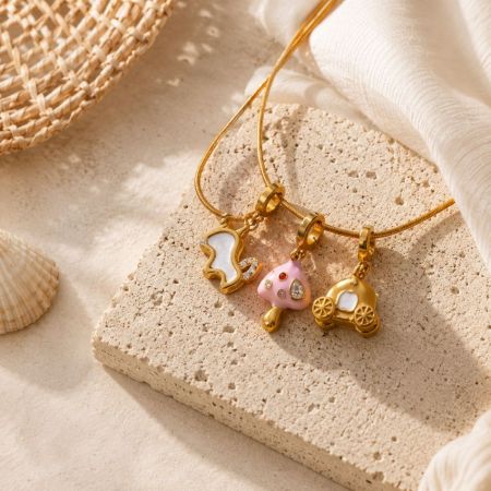 Collar de cadena de oro con encantos de esmalte personalizados en un bloque de piedra texturizado, destacando diseños de joyería versátiles.
