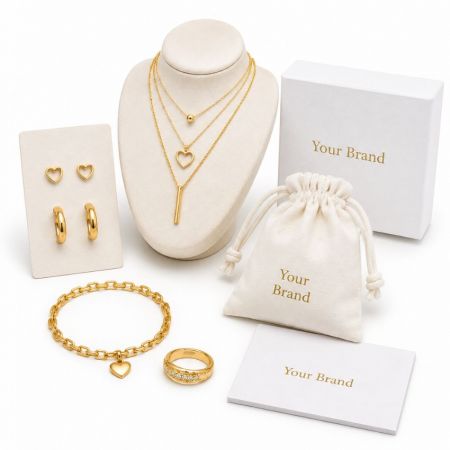 Custom layered gold necklaces, heart earrings, and bracelets displayed with branded B2B wholesale packaging.