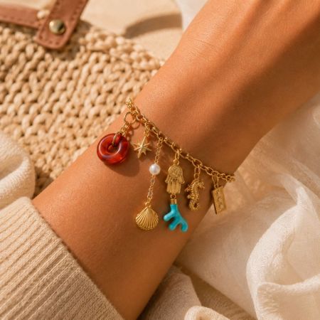 Bracelet en chaîne en or avec des charms océaniques polyvalents comme des pendentifs en corail, hippocampe et coquillage.