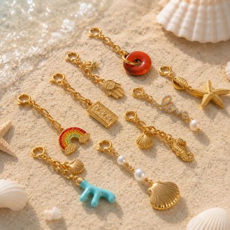Dix designs uniques de charms océaniques en or disposés sur le sable, idéaux pour les acheteurs de sourcing en gros à faible MOQ.