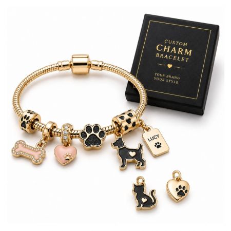 Custom pet charm bracelet with gold dog paw, bone, and name tag charms beside a black private label gift box.