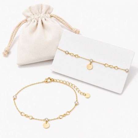 Gold infinity link charm bracelet displayed with a fabric pouch, ideal for premium gift jewelry manufacturing.