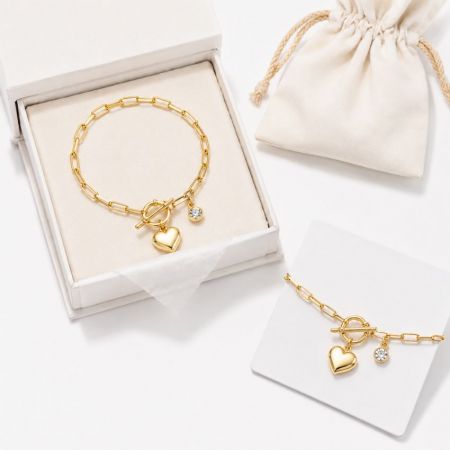 Gold heart charm toggle clasp bracelet with a gift box and pouch, designed for luxury brand jewelry sourcing.
