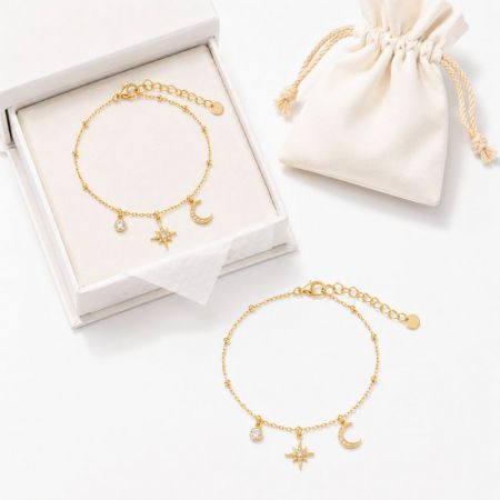 Gold celestial star and moon charm bracelets next to a gift pouch, excellent for seasonal jewelry collections.