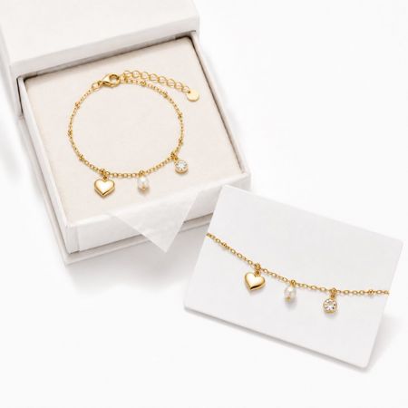 Gold heart and pearl charm bracelet with packaging, a sophisticated option for corporate gifting suppliers.