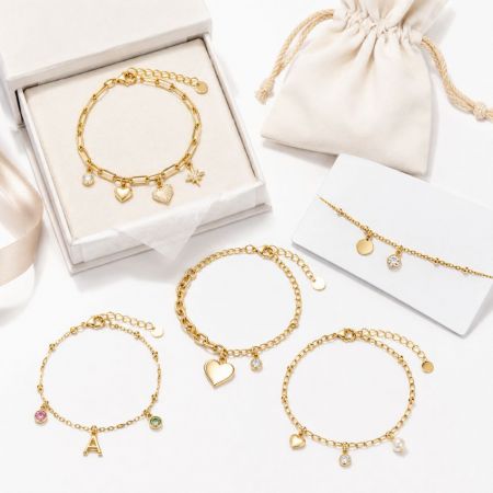 Assorted gold charm bracelets including heart, star, and initial designs with luxury packaging for B2B sourcing.