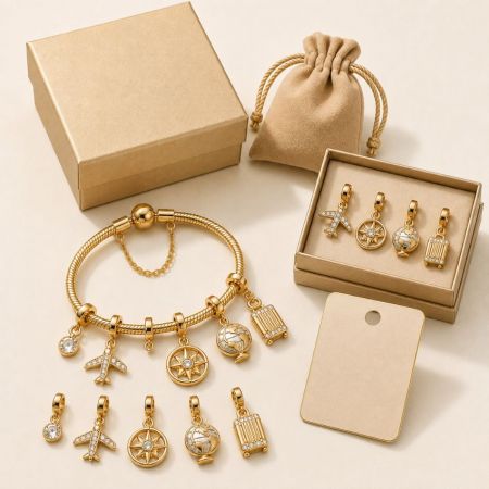 Travel themed gold charm bracelet featuring airplane and globe pendants, displayed alongside premium packaging boxes.