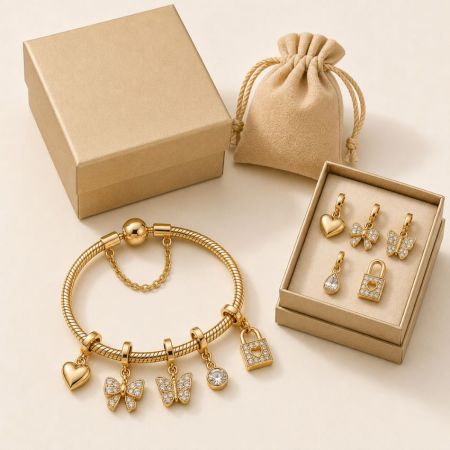 Gold butterfly and heart charm bracelet with crystal accents, shown with velvet pouch and gift box for retail B2B.