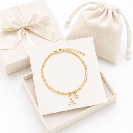 Double-layered gold chain bracelet with letter A and crystal charms, displayed for custom jewelry manufacture.