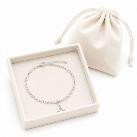 Silver cable chain bracelet with a letter A charm in a velvet display box, suitable for private label jewelry.