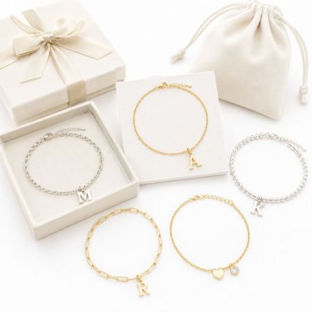 Assorted gold and silver initial charm bracelets with custom gift boxes, showcasing OEM/ODM jewelry capabilities.