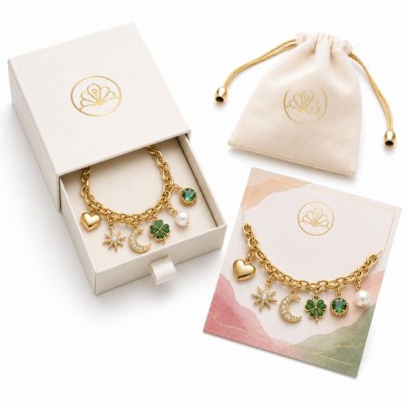 Gold link chain bracelet featuring four-leaf clover, crescent moon, and star charms next to wholesale premium gift box.