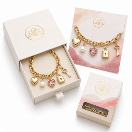 Custom gold chain bracelet with key, padlock, and pink crystal charms, ideal for B2B boutique jewelry retail supply.