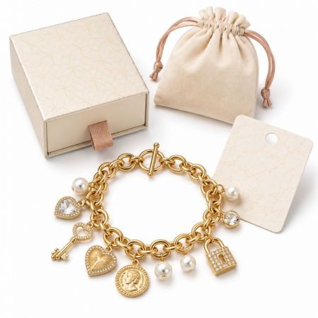 Charm Fashion Jewelry - Gold charm bracelet with pearl, heart, padlock, and key pendants, alongside wholesale presentation box and pouch.