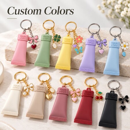 Assorted custom color silicone cosmetic tube keychains with matching enamel charms for OEM supply.