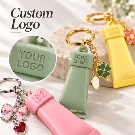 Close-up of embossed brand logo on custom silicone cosmetic tube keychain caps for promotional merchandise.