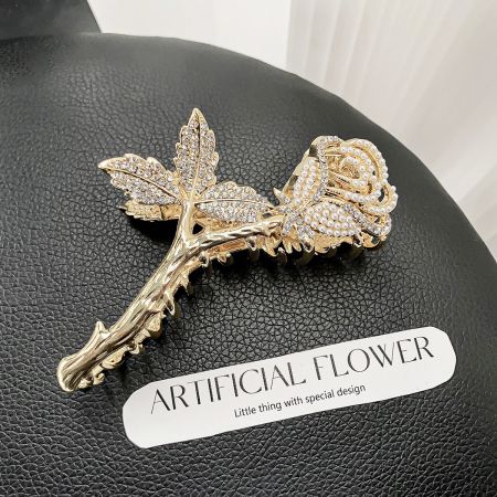 A beautiful gold rose hair clip with delicate rhinestone and pearl details on a black background.