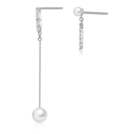 Vue en gros plan montrant le design asymétrique des boucles d'oreilles en perles et zircon cubique, avec une plus longue que l'autre.