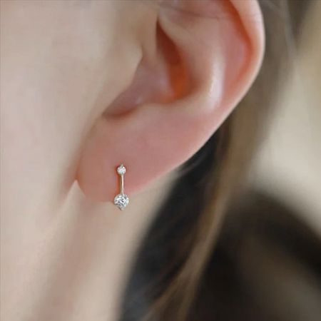 Un primo piano dettagliato di un singolo orecchino huggie in zirconia in argento sterling 925, evidenziando la montatura della pietra.