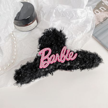 Close-up de um clipe de cabelo de pelúcia rosa com tema da Barbie e detalhes em strass.