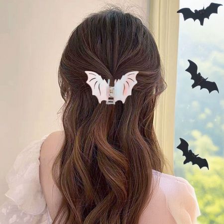 Une femme aux longs cheveux bruns portant une pince à cheveux en forme de chauve-souris blanche, montrant l'accessoire en usage.